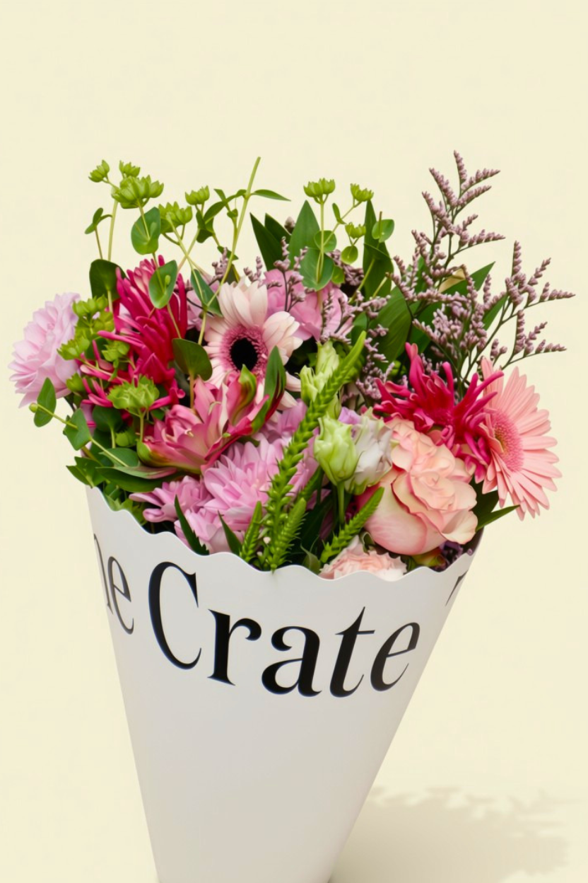 The Crate seasonal flower delivery Ireland featuring fresh pink gerberas, garden roses, and lush greenery in a white signature presentation cone.
