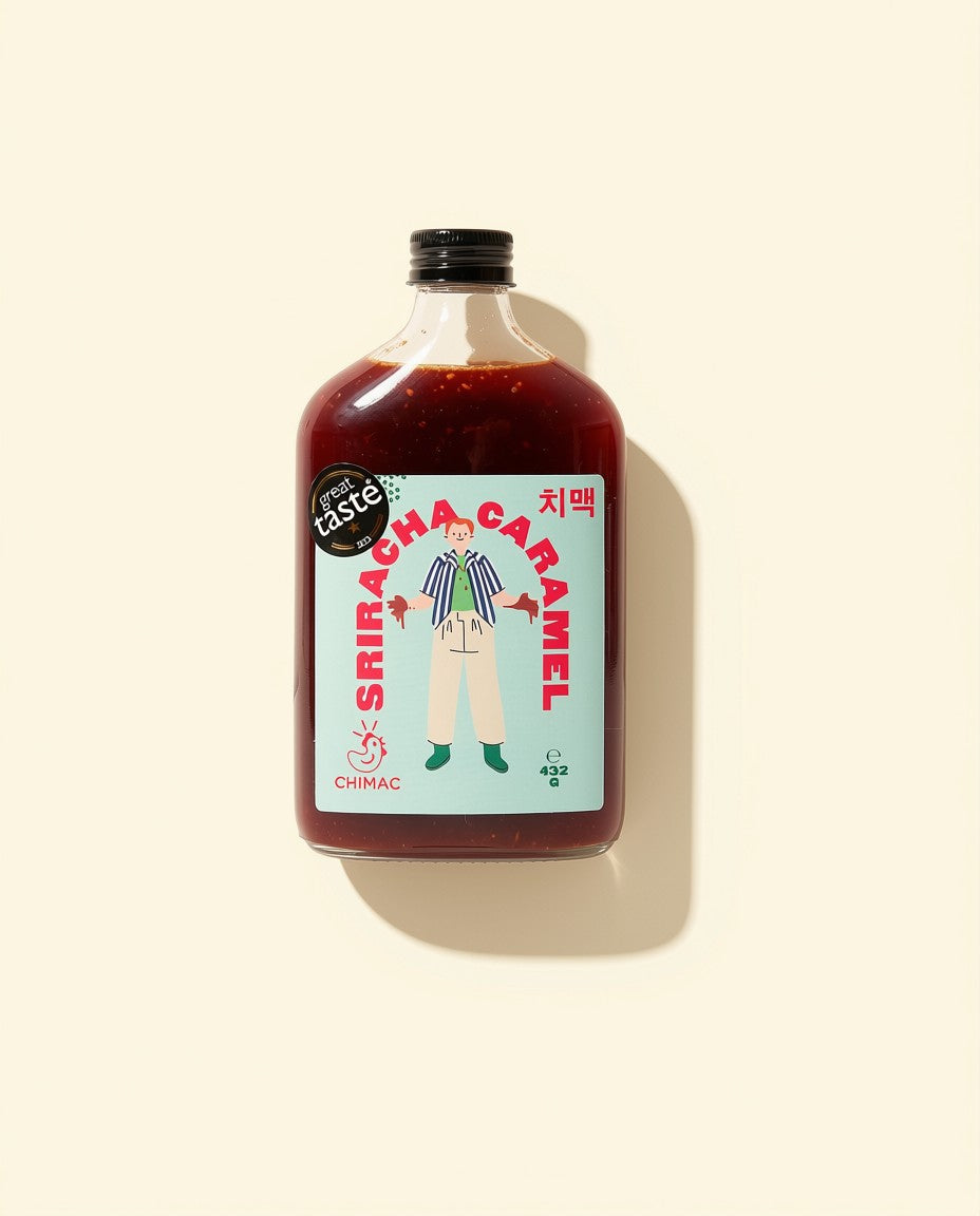 A bottle of CHIMAC Sriracha Caramel sauce with a black cap, set against a solid cream background with a soft shadow. The label features a light blue background with red text and an illustration of a person.